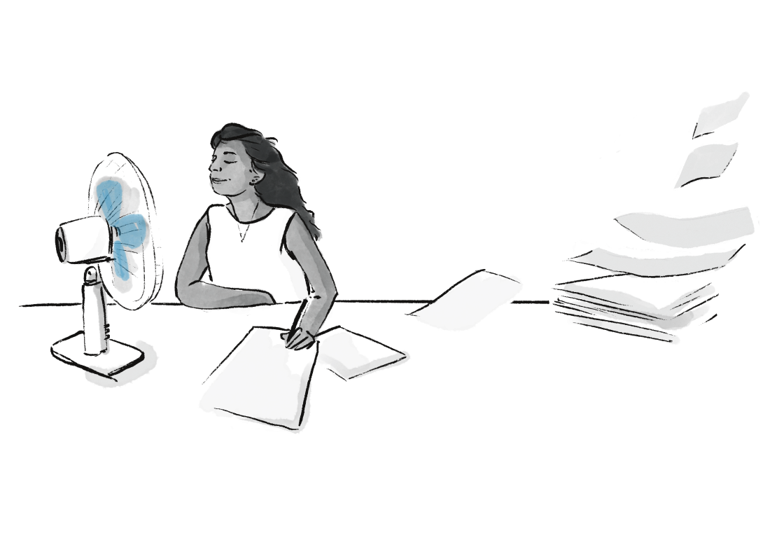 Woman sitting at a desk with a fan blowing documents on the floor